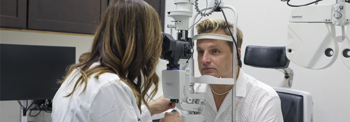 Dr. Melissa Dugan performs a detailed vision exam using diagnostic equipment in a clinic room.